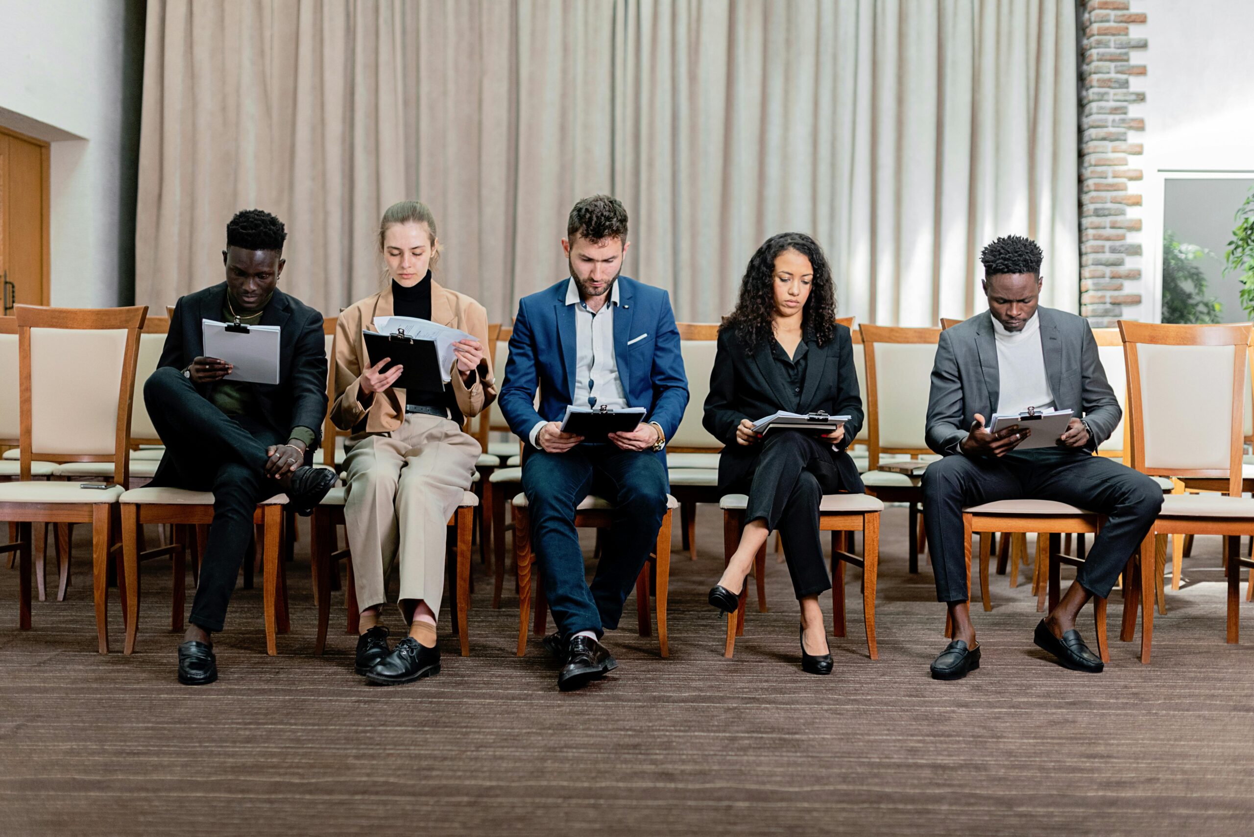 Job candidates seated in a waiting area reviewing documents before an interview